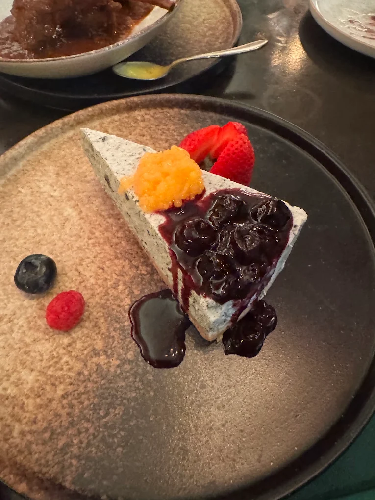 Black sesame cheesecake with berry coulis, strawberries, and fruit caviar