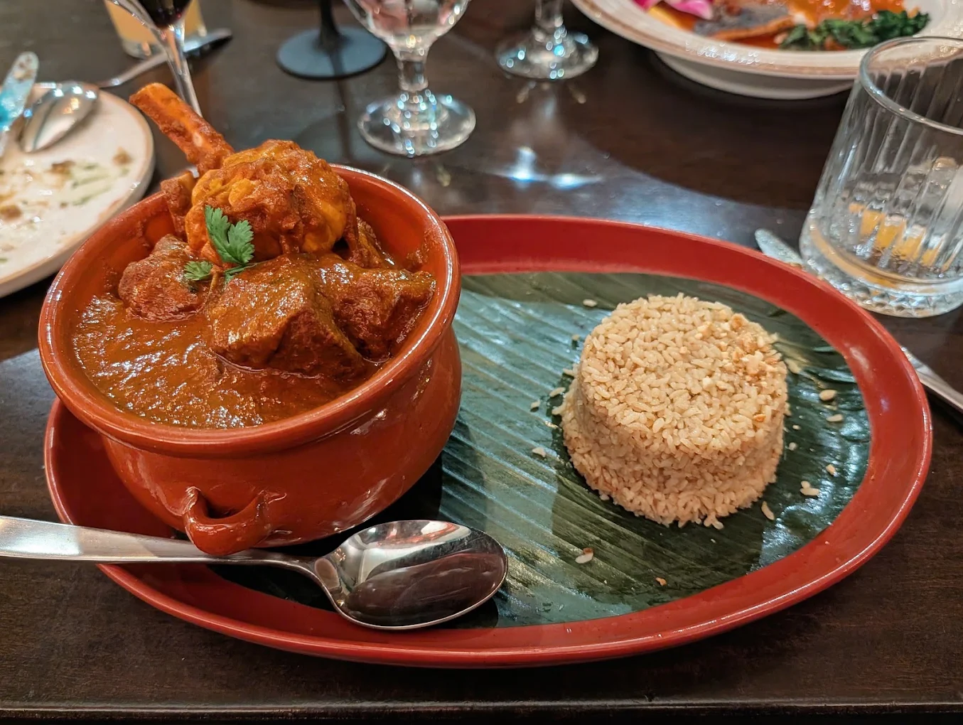 Claypot Goat Chops — goat chop curry in a red claypot with sweet pulao on a banana leaf