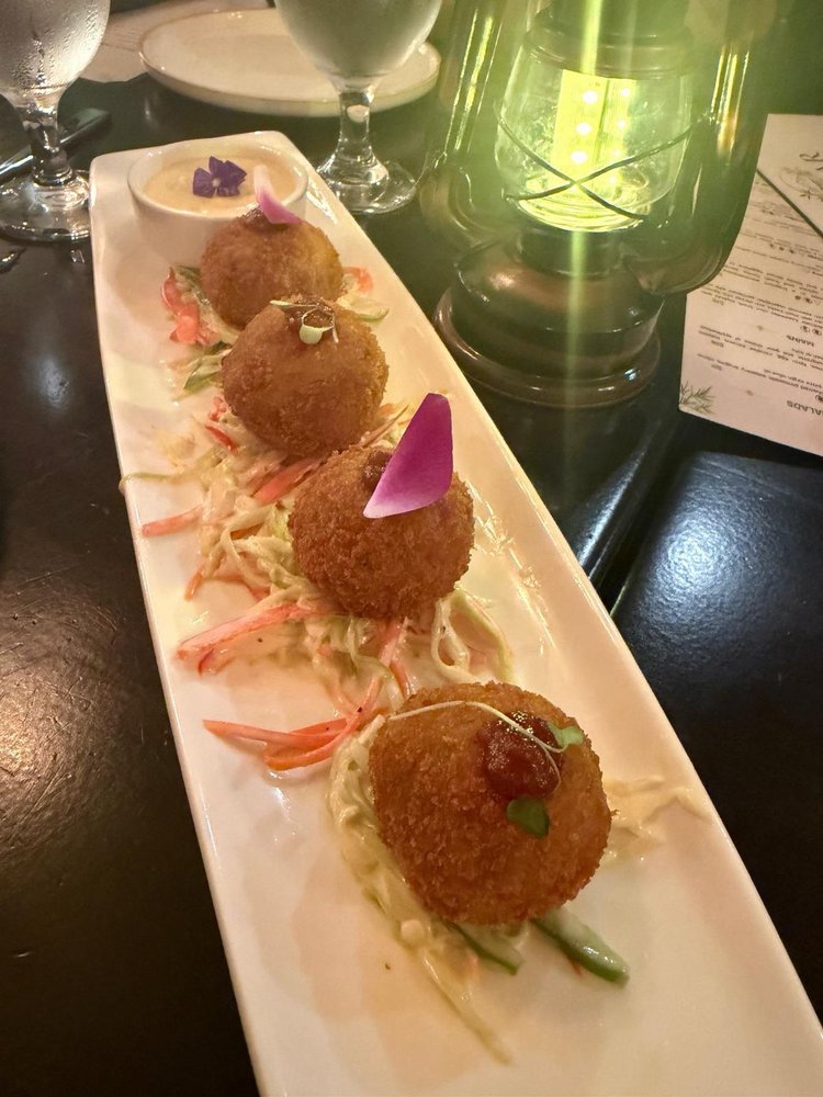 Signature Khaar Croquette — golden croquettes over slaw on a white platter with a dipping sauce
