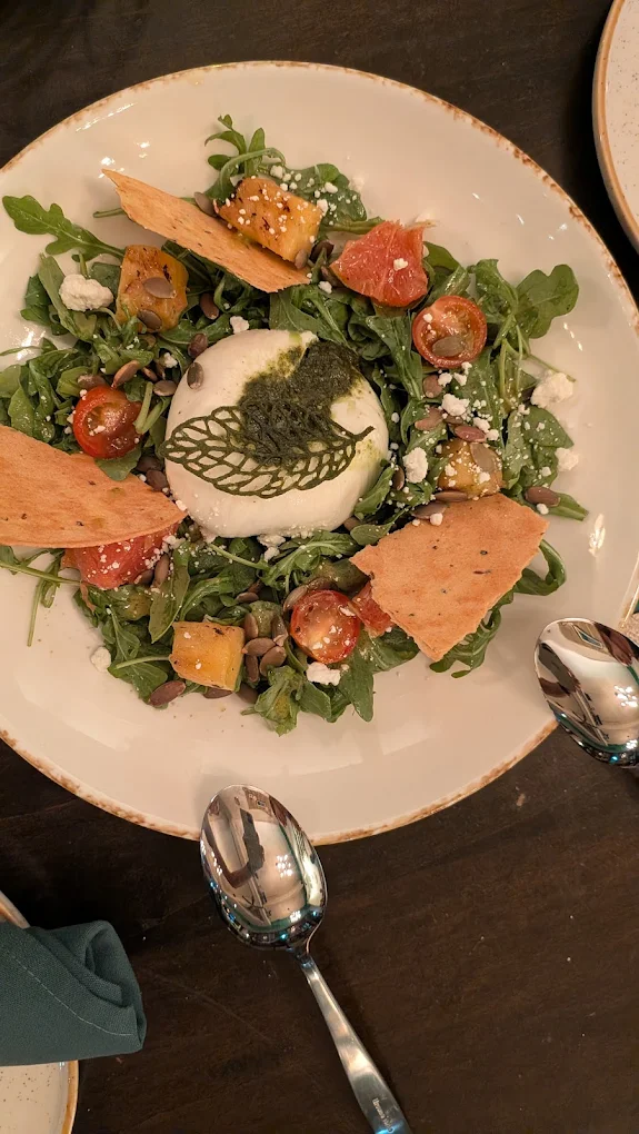 Orchard Burrata salad — creamy burrata over arugula with citrus, charred pineapple, and seed crisps