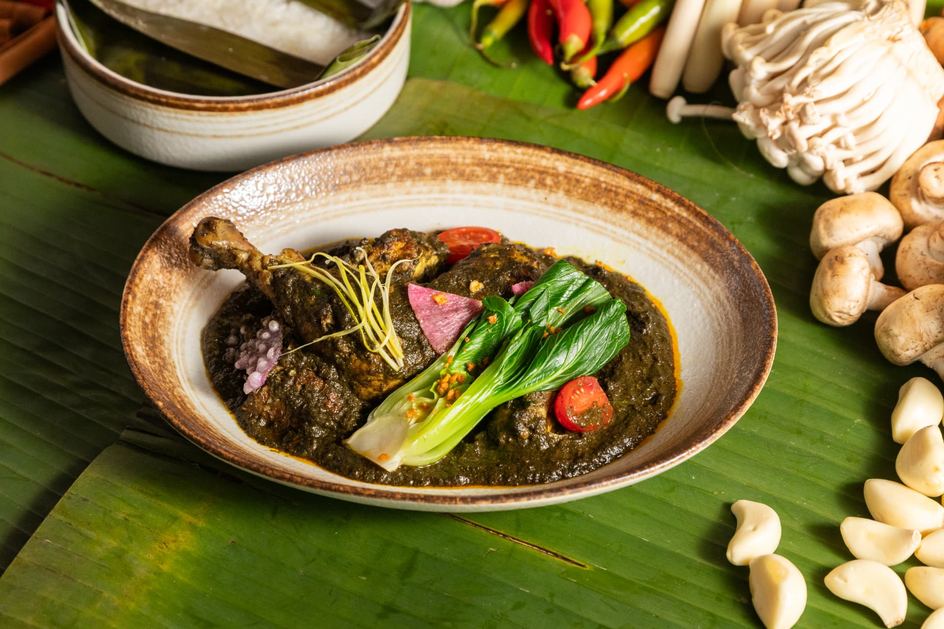 Dark green chicken curry with bok choy on a banana leaf