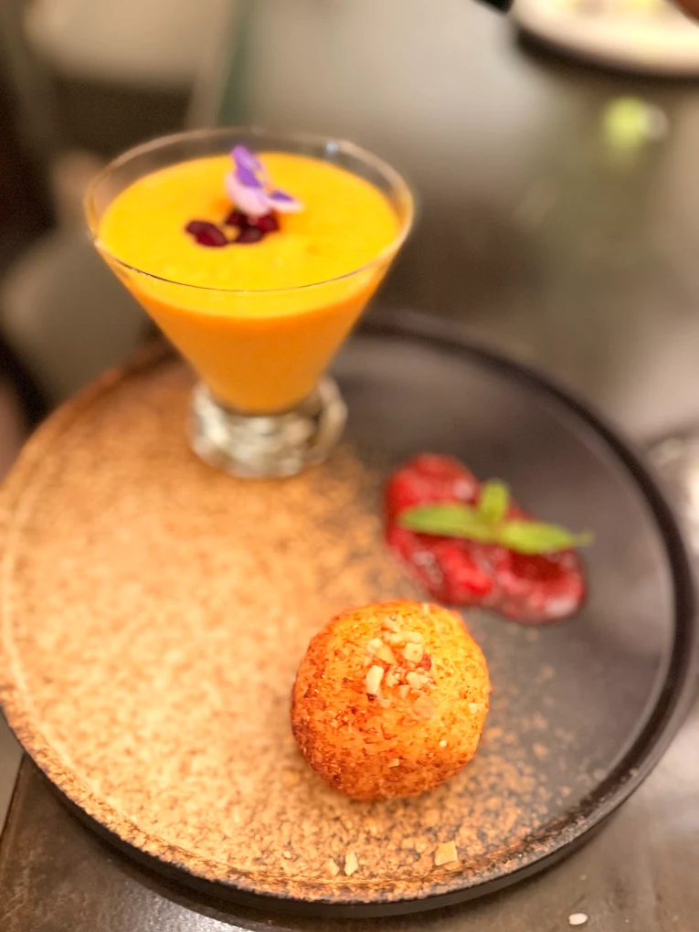 Mango dessert in a glass with a golden crisp on the plate
