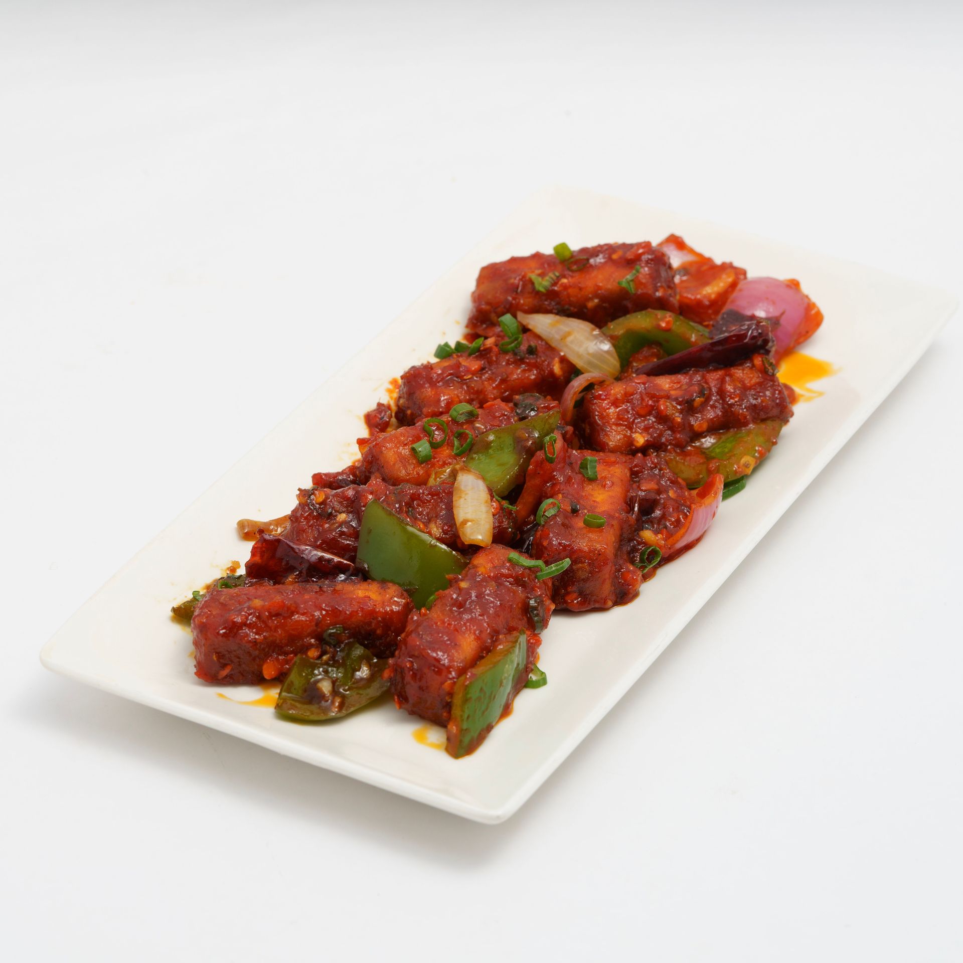 Delicious spicy Indo-Chinese chili paneer served on a white plate. Perfect appetizer or side dish.